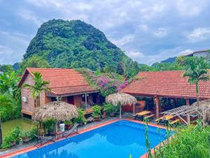 a villa with a swimming pool in front of a mountain at Trang An Village Homestay in Ninh Binh