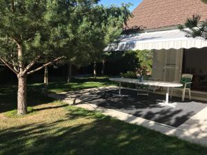 a picnic table in front of a house with a tree at 2 chambres adjacentes dans villa avec jardin de pins in Commugny