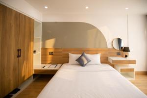 a bedroom with a large white bed with a wooden headboard at FIRST Studio Hotel in Da Nang