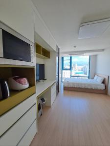 a bedroom with a bed and a desk with a television at Joongmoon ocean stay in Seogwipo