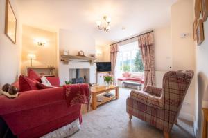 uma sala de estar com um sofá vermelho e uma cadeira em Chimney Pots cottage em Youlgreave