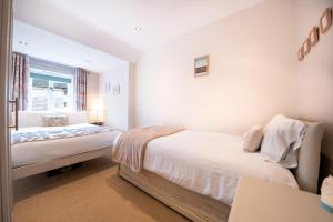um quarto branco com 2 camas e uma janela em Chimney Pots cottage em Youlgreave