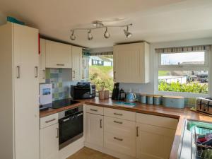 a kitchen with white cabinets and a window at Ammonite in Lyme Regis