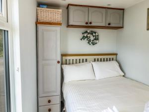 a small bedroom with a bed and a cabinet at Ammonite in Lyme Regis