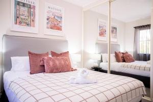 a white bedroom with a bed and a mirror at Stunning Northbridge Townhouse W Off St Parking in Perth