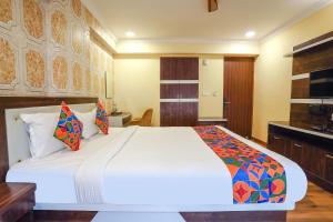 a bedroom with a large white bed with colorful pillows at FabHotel Prime Signature Inn in Bangalore