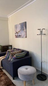 - un salon avec un canapé bleu et un tabouret dans l'établissement Haz Furnished Apartments Buwate, à Kampala