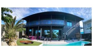 una grande casa di vetro con una piscina di fronte di ＩＲＡＧＯ　ＡＲＴ　 ＨＯＴＥＬ 　THECAPE a Irago