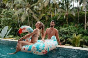 a man and a woman are sitting on an inflatable at Dedary Resort & Spa Ubud by Ini Vie Hospitality in Ubud +41 photos