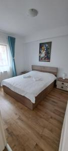 un grande letto in una camera da letto con pavimento in legno di Apartament Sânpetru-Brașov a Sînpetru