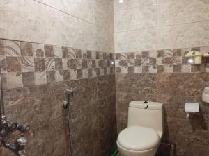 La salle de bains est pourvue de toilettes et d'un mur carrelé. dans l'établissement Islamabad Premium Hotel, à Islamabad