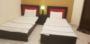 2 camas en una habitación de hotel con almohadas blancas y rojas en Regal Guest House, en Bahawalpur