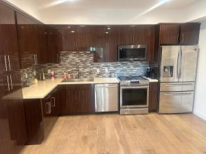 una cocina con armarios de madera y electrodomésticos de acero inoxidable en New and Bright Bedroom Ensuite, en Los Ángeles