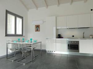 a kitchen with white cabinets and a table with chairs at Acqua Dolce Comfortable holiday residence in Sala Comacina