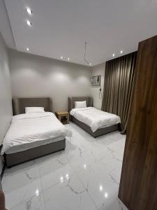 two beds in a room with white tile floors at Al Amer Apartment2 in Jeddah +4 photos