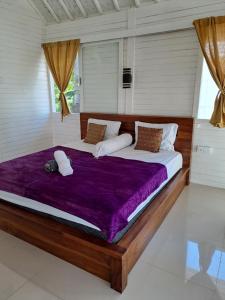 ToyapakehにあるThe Palms Penidaのベッドルーム1室(大型ベッド1台、紫色の掛け布団付)