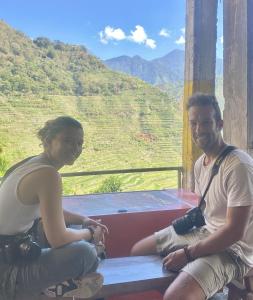 een man en een vrouw op een bank met een berg bij Batad Pension and Restaurant in Banaue
