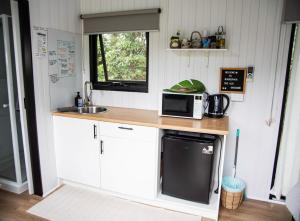 uma cozinha com um balcão com um micro-ondas e um lavatório em Binderaga Old Orchard em Bilpin
