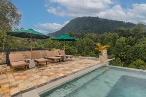 una piscina con sillas y sombrillas junto a una montaña en Munduk Kupang Sekumpul Villa, en Singaraja