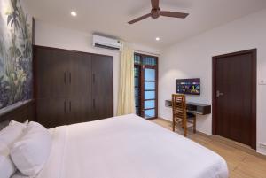 1 dormitorio con 1 cama blanca grande y escritorio en Reach Homes, en Kochi
