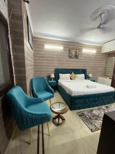 a bedroom with a bed and two blue chairs at Divine India Service Apartment 3 BHK D-198 Saket in New Delhi