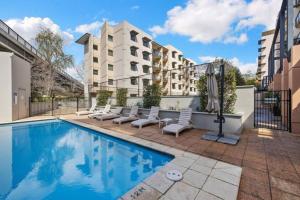 a swimming pool with chairs and a building at Luxurious Perth CBD Apt c Kings Park Free Parking in Perth