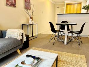 uma sala de estar com um sofá, uma mesa e cadeiras em Prime Location 1 Bdr Apt in Perth em Perth