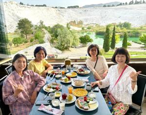 帕莫卡萊的住宿－Pamukkale Sahin Boutique Hotel，一群坐在餐桌上吃食物的妇女