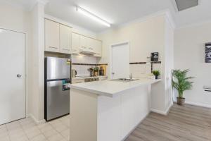 kuchnia z białymi szafkami i lodówką ze stali nierdzewnej w obiekcie East Perth Apartment with Free Wi-Fi and Parking w mieście Perth