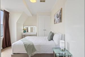 biała sypialnia z łóżkiem i szklanym stołem w obiekcie East Perth Apartment with Free Wi-Fi and Parking w mieście Perth