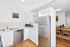 パースにあるExecutive Apt - 2BR 1BA w Parkingのキッチン(ステンレス製の冷蔵庫、白いキャビネット付)
