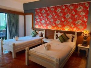 a room with two beds and a red wall at Bhumiyama Plus in Ko Chang
