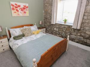 a bedroom with a bed with a wooden frame and a window at Fern Cottage in Cardiff