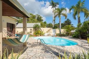 a swimming pool with a hammock next to a house at lapislazuli in Saint-Paul