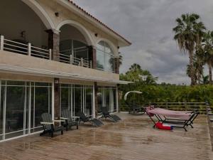 una casa con sillas y mesas en una terraza en Lujosa Villa en Casa de Campo Golf & Resort, La Romana Brre#15, en La Romana