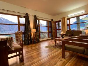 un soggiorno con ampie finestre e pavimenti in legno di Kamal Guest house a Vapi