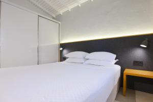 a bedroom with a large bed with white sheets and pillows at AEGEAN Apartments - Bungalows in Alacati