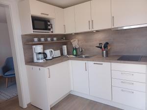 a kitchen with white cabinets and a sink and a microwave at FeWo Seeadler - Heuser Prerow in Prerow