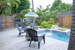 una terraza con sillas y una sombrilla junto a la piscina en villa australina, en Saint-Paul