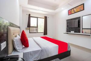 una camera da letto con un letto con cuscini rossi e una TV di Hotel Raj Ganga Haridwar Near Raja Ji National park Jeep Safari - Excellent Customer Choice- Best Seller a Haridwār