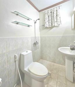 a white bathroom with a toilet and a sink at Eagles Nest Beach Resort in Davao City