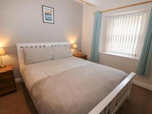 a bedroom with a bed and a window with blue curtains at Oak Cottage in Appleby