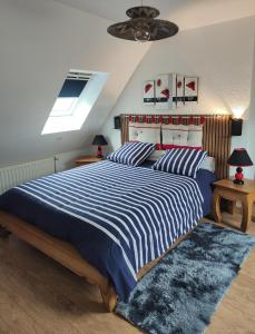 a bedroom with a large bed with blue and white stripes at GÎTE DE LA FONTAINE in Wangen