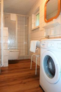 uma máquina de lavar roupa na casa de banho com banheira em Ferienhaus Eulennest - Ulenhoef em Prerow