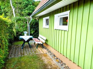 uma casa verde com uma mesa e um banco ao lado em Ferienhaus Eulennest - Ulenhoef em Prerow