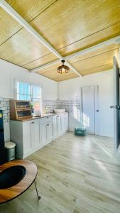 cocina grande con armarios blancos y techo de madera en บ้านไร่ฟ้าสวยวังน้ำเขียว Nordic 01 en Ban Kom