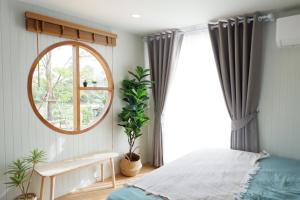 1 dormitorio con cama y ventana redonda en บ้านไร่ฟ้าสวยวังน้ำเขียว Nordic 01 en Ban Kom