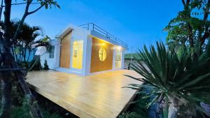 una casa pequeña en una terraza de madera con luz en บ้านไร่ฟ้าสวยวังน้ำเขียว Nordic 01 en Ban Kom