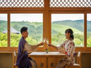 un uomo e una donna seduti a un tavolo con bicchieri da vino di Hotel New Wakasa a Nara