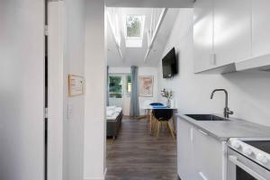 a kitchen with white cabinets and a living room at Holiday Apartment At Beautiful Solgaarden 6 in Svaneke